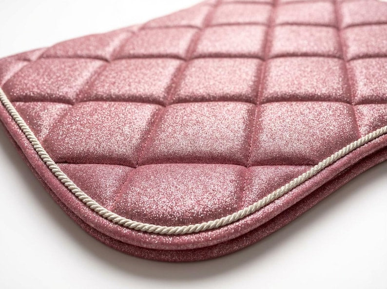 Close-up of pink glitter diamond-quilted saddle pad with white rope trim
